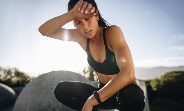 Erschöpfte Sportlerin wischt sich nach dem Training den Schweiß ab