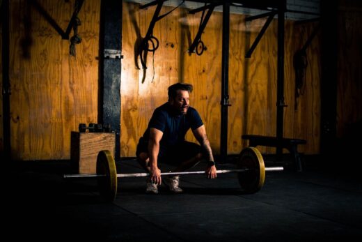 Mann hebt im Fitnessstudio eine mit Gewichtsscheiben beladene Langhantel