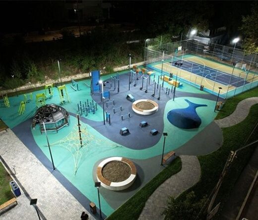 Beleuchteter urbaner Sportpark mit Fitnessgeräten und Basketballfeld