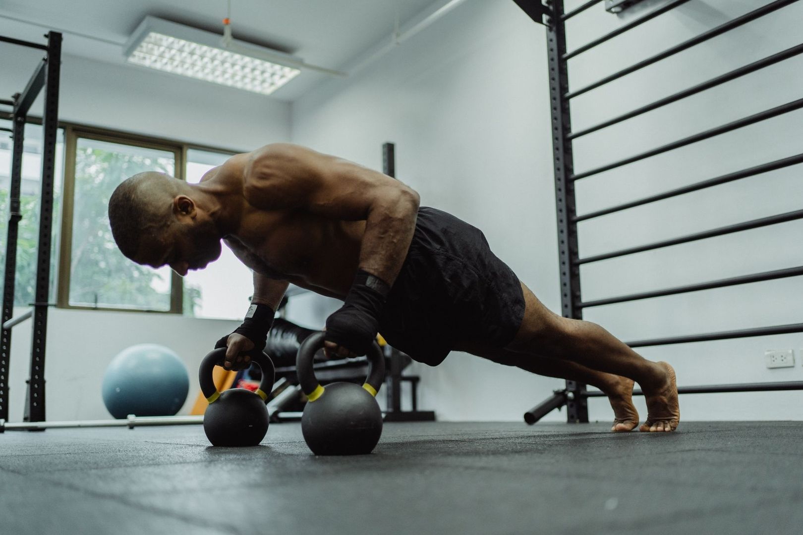 Mann stützt sich im Fitnessstudio auf zwei Kettlebells